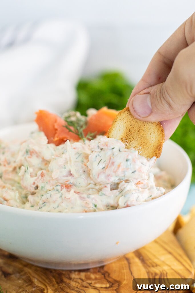 Salmon and Cream Cheese Dip & Spread: Lox-Style Appetizer Recipe 4 Bagel chip dipping into a bowl of smoked salmon dip sitting on a cutting board.