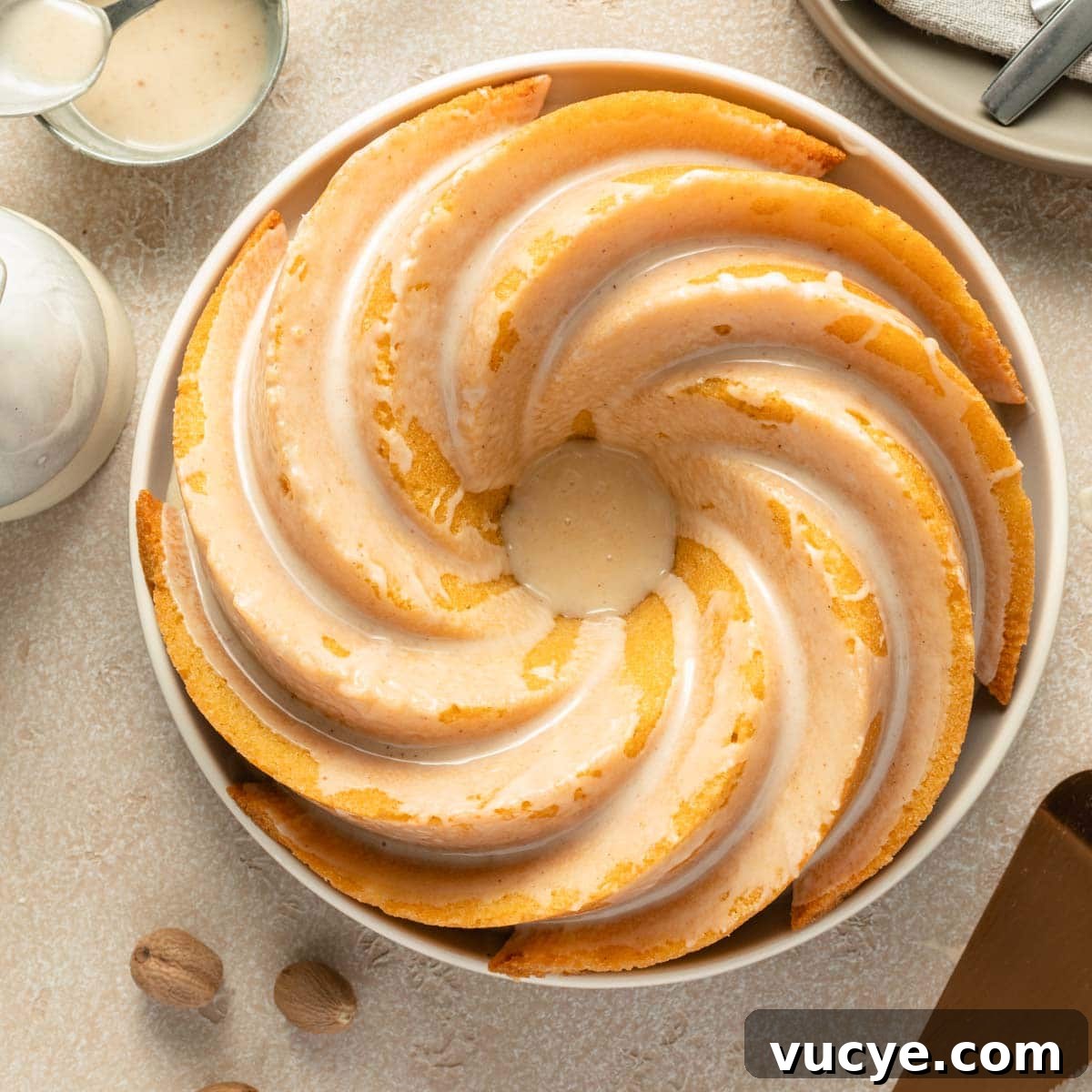 Eggnog Bundt Cake Recipe with Spiced Rum Glaze 8 Overhead view of an eggnog bundt cake topped with glaze on a round plate.