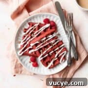 Red Velvet Waffles Recipe: fluffy, rich, and irresistible 12 A square shot of a white plate of red velvet waffles with cream cheese drizzle and pecans.