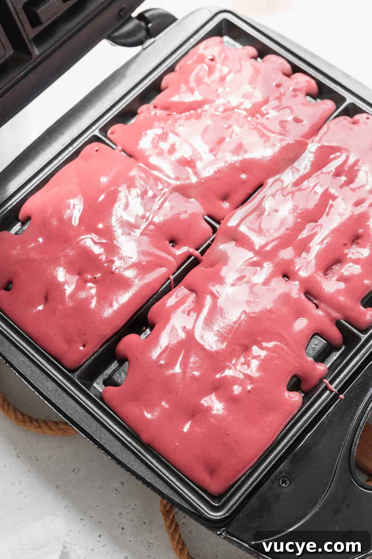 Red Velvet Waffles Recipe: fluffy, rich, and irresistible 7 A waffle maker filled with red velvet waffle batter.