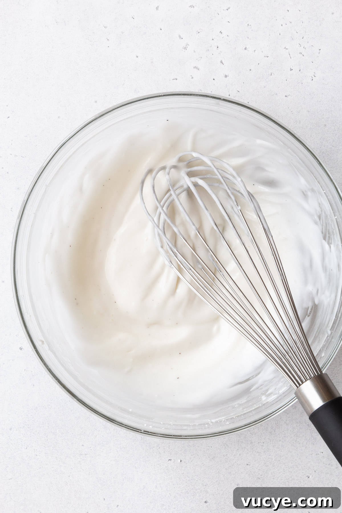 Red Velvet Waffles Recipe: fluffy, rich, and irresistible 10 A glass mixing bowl of the cream cheese glaze with a whisk.