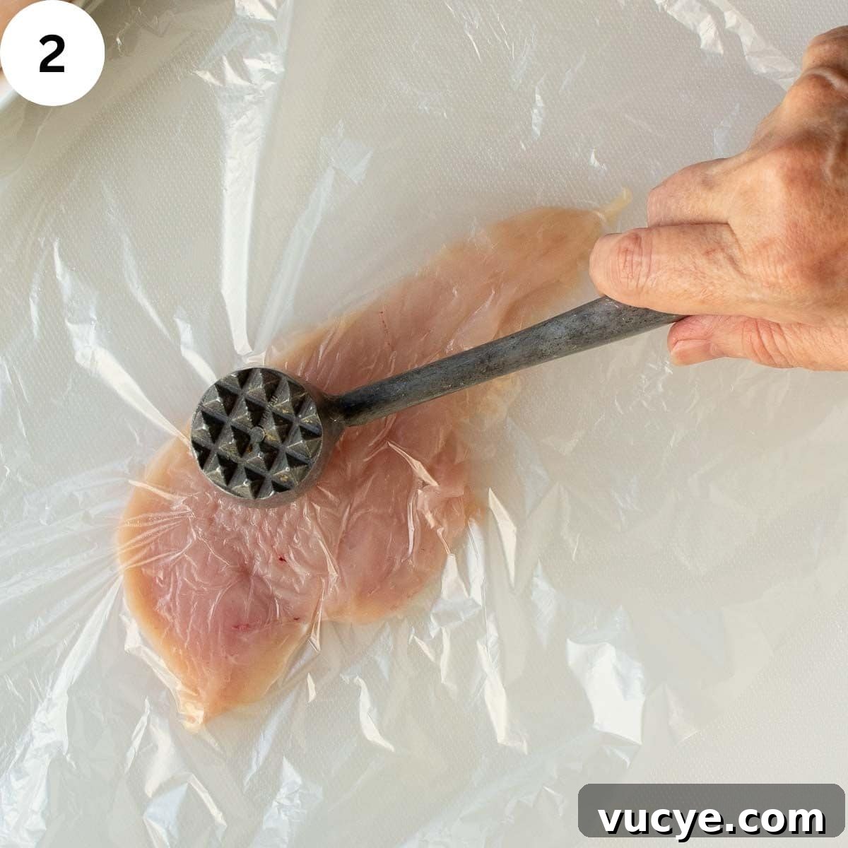 Pounding chicken breast with meat mallet.