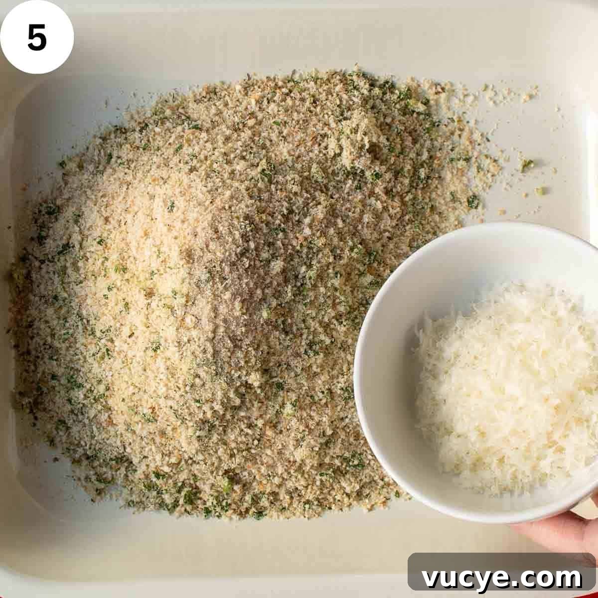 Adding finely grated cheese to breadcrumbs.