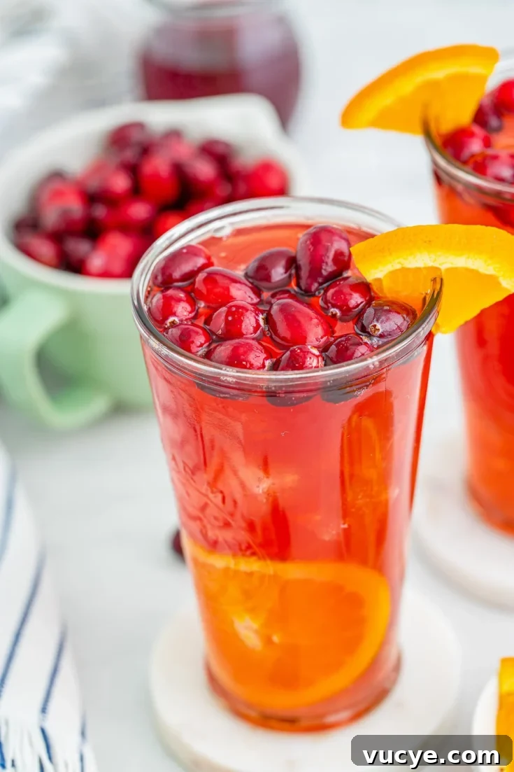 A cranberry orange rum punch cocktail garnished with cranberries and orange slices.