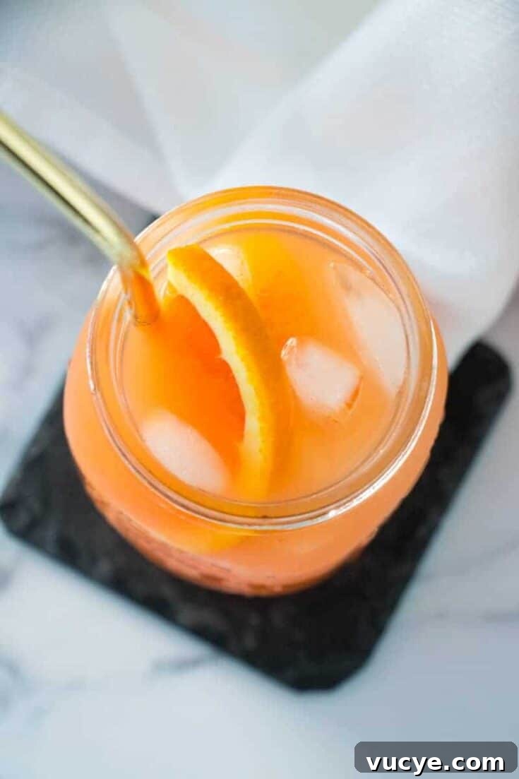 An orange Christmas rum punch cocktail on a white table.