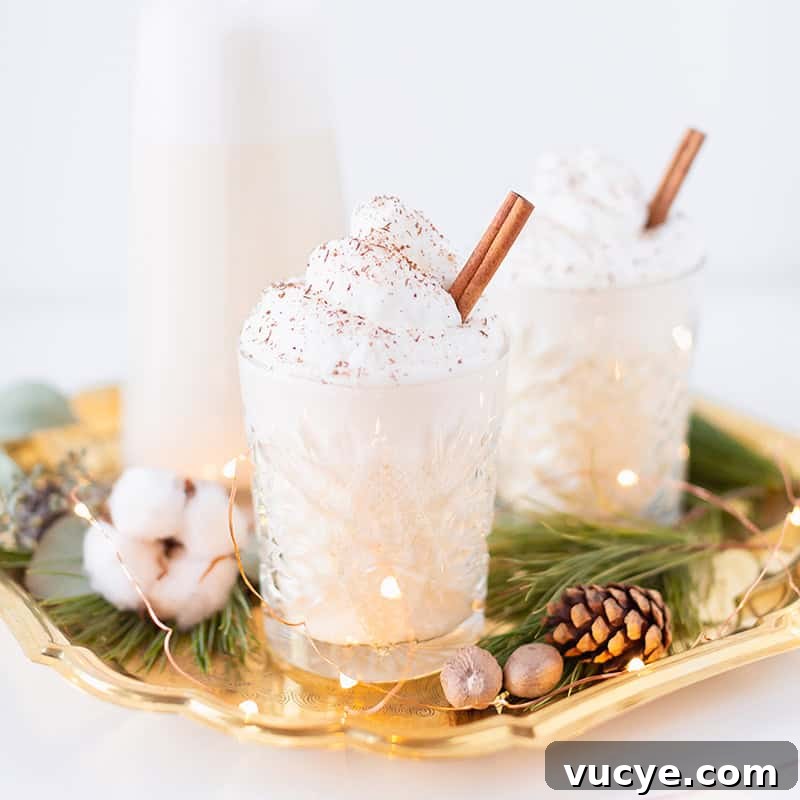 A coconut rum eggnog cocktail topped with whipped cream and a cinnamon stick.