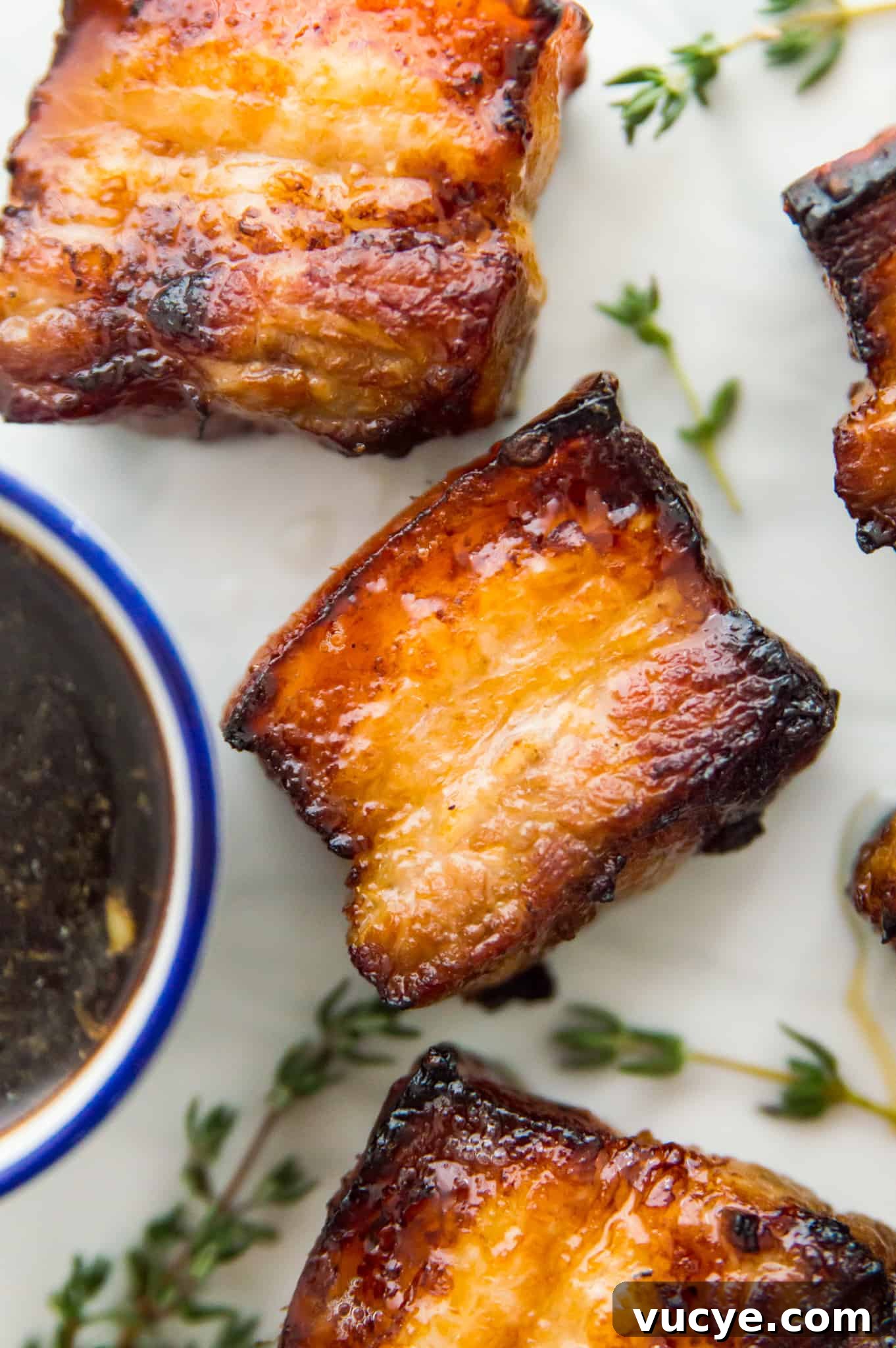 Crispy Air Fryer Pork Belly Bites — Quick Savory Recipe 2 Three pieces of cooked pork belly on a plate with fresh thyme around them.