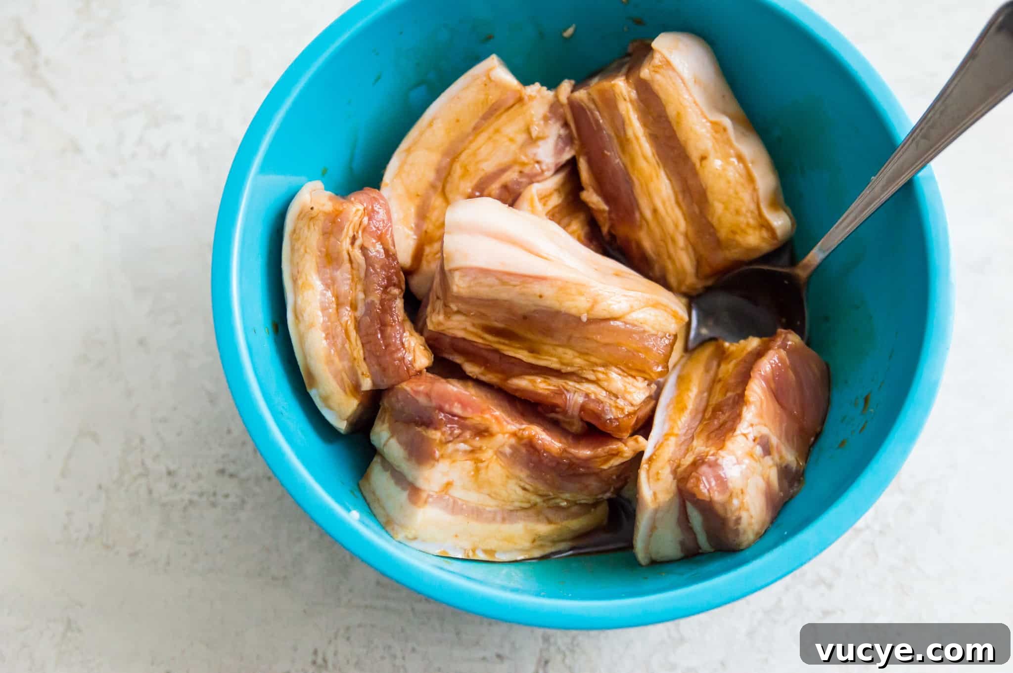 Crispy Air Fryer Pork Belly Bites — Quick Savory Recipe 6 Pork belly strips being coated in a marinade in a bowl.