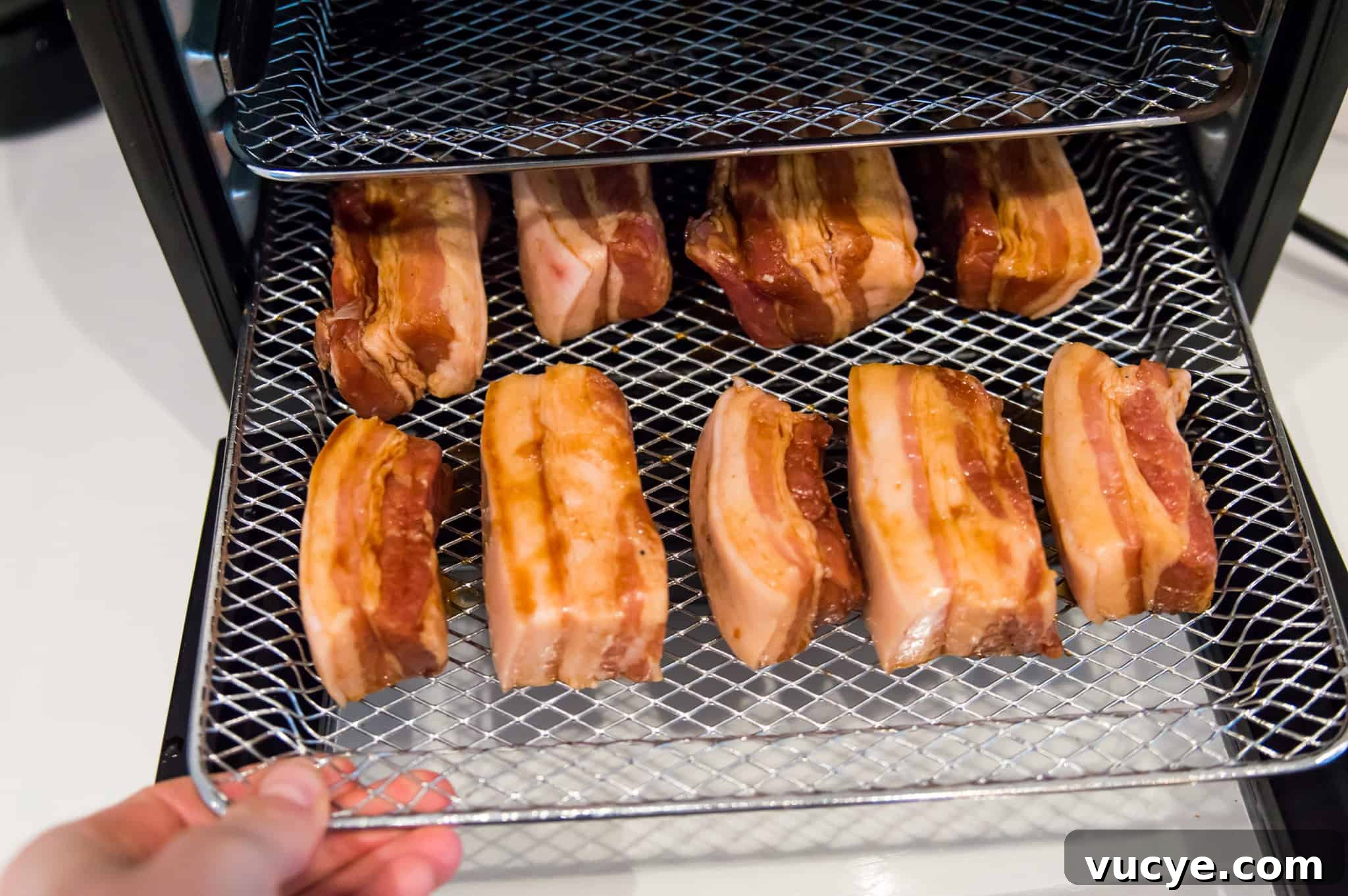 Crispy Air Fryer Pork Belly Bites — Quick Savory Recipe 7 Marinated pork belly pieces on an air fryer rack.