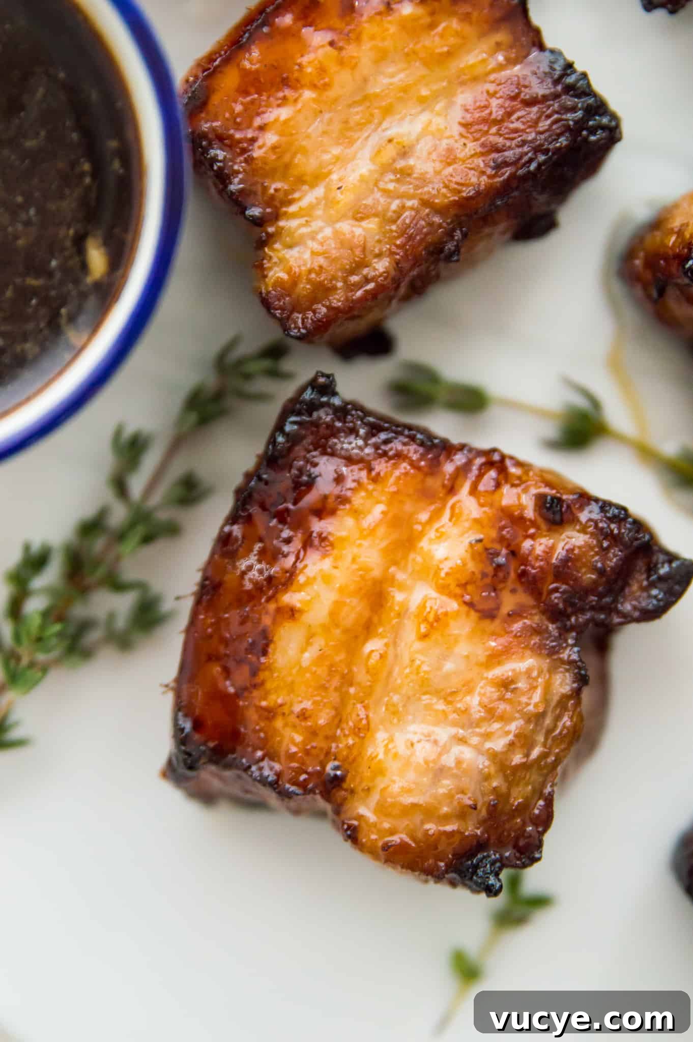 Crispy Air Fryer Pork Belly Bites — Quick Savory Recipe 8 Cooked pork belly pieces on a plate with a bowl of soy sauce beside it.