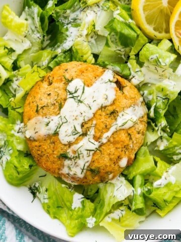 A salmon cake on a bed of lettuce drizzled with aioli sauce.