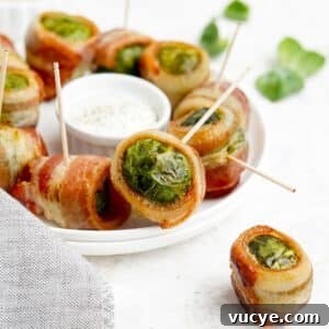 Bacon wrapped brussels sprouts on the table on a plate with a sauce in the middle.