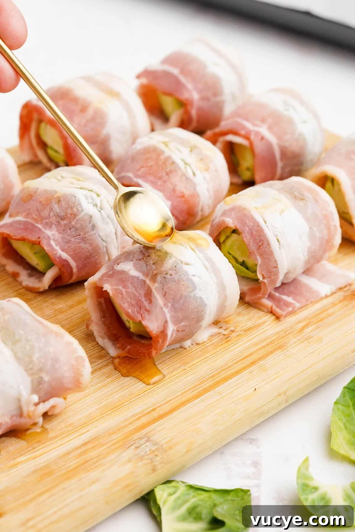 Drizzling maple syrup over the top of the bacon wrapped brussels sprout.
