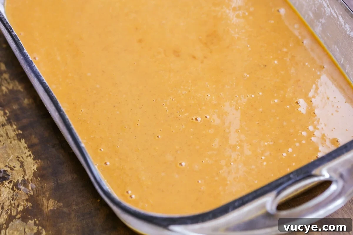 Ultimate Pumpkin Crunch Cake Recipe for Fall Dessert 2 Pumpkin cake batter poured into a baking dish.