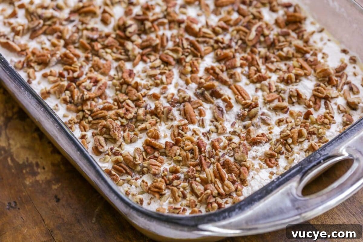 Ultimate Pumpkin Crunch Cake Recipe for Fall Dessert 4 Adding nuts on top of pumpkin layer of pumpkin crunch cake.