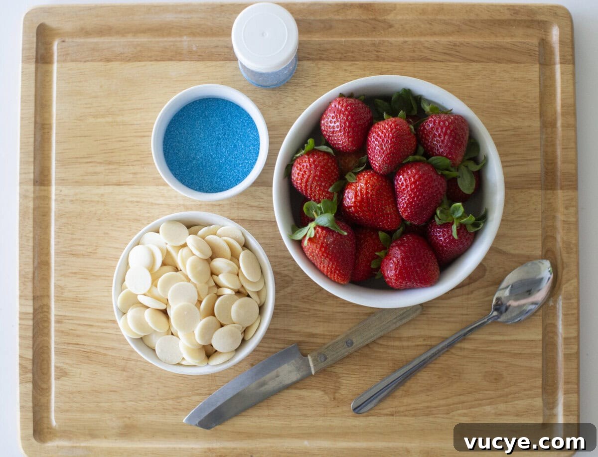 Red, White & Blue Dipped Strawberries for 4th of July 3 A wooden cutting board with a bowl of fresh strawberries, a bowl of white chocolate melts, a bowl of blue sprinkles, a container of blue sprinkles, a metal spoon, and a knife.