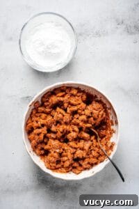 Crunchy Peanut Butter Muddy Buddies Recipe 5 Chex cereal coated in chocolate and peanut butter, with a bowl of powdered sugar nearby.