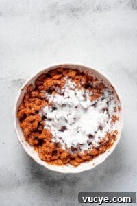 Crunchy Peanut Butter Muddy Buddies Recipe 6 Powdered sugar dumped in a bowl of coated cereal.