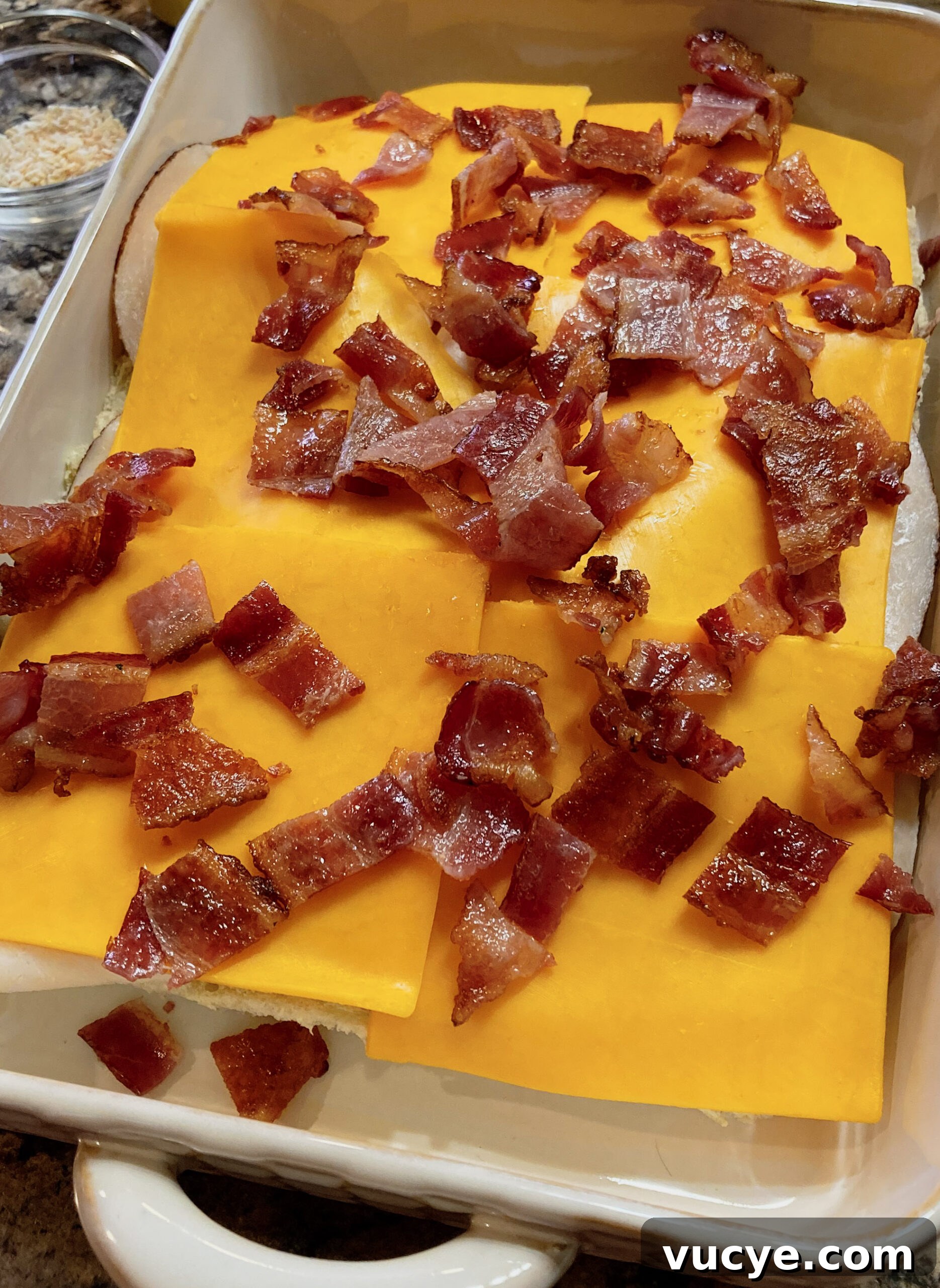 Chicken Bacon Ranch Sliders Recipe: Savory Mini Sandwiches 5 Cheese and bacon topping the chicken and hawaiian rolls, waiting to be topped and baked.