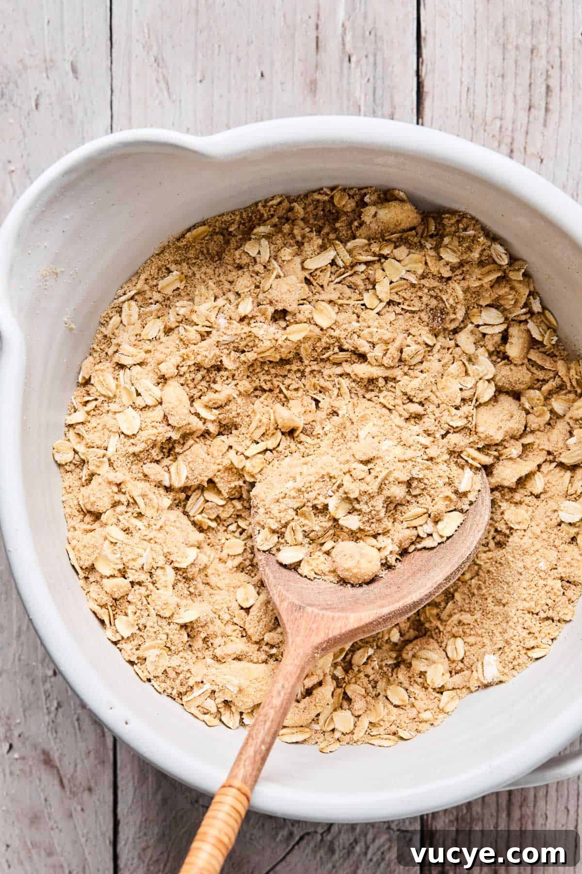 Naturally Sweetened Gluten-Free Berry Crisp Recipe 9 oats being stirred into flour, cinnamon, brown sugar mixture for gluten free berry crisp topping