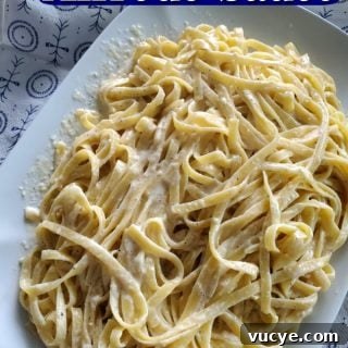 Olive Garden Alfredo Sauce text over a large platter of fettuccine alfredo