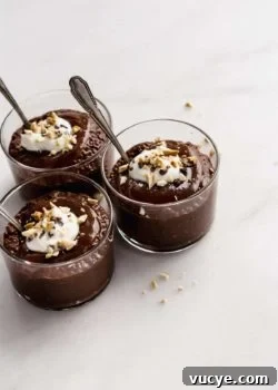 three cups of snickers chia pudding topped with yogurt, peanuts and cocoa nibs