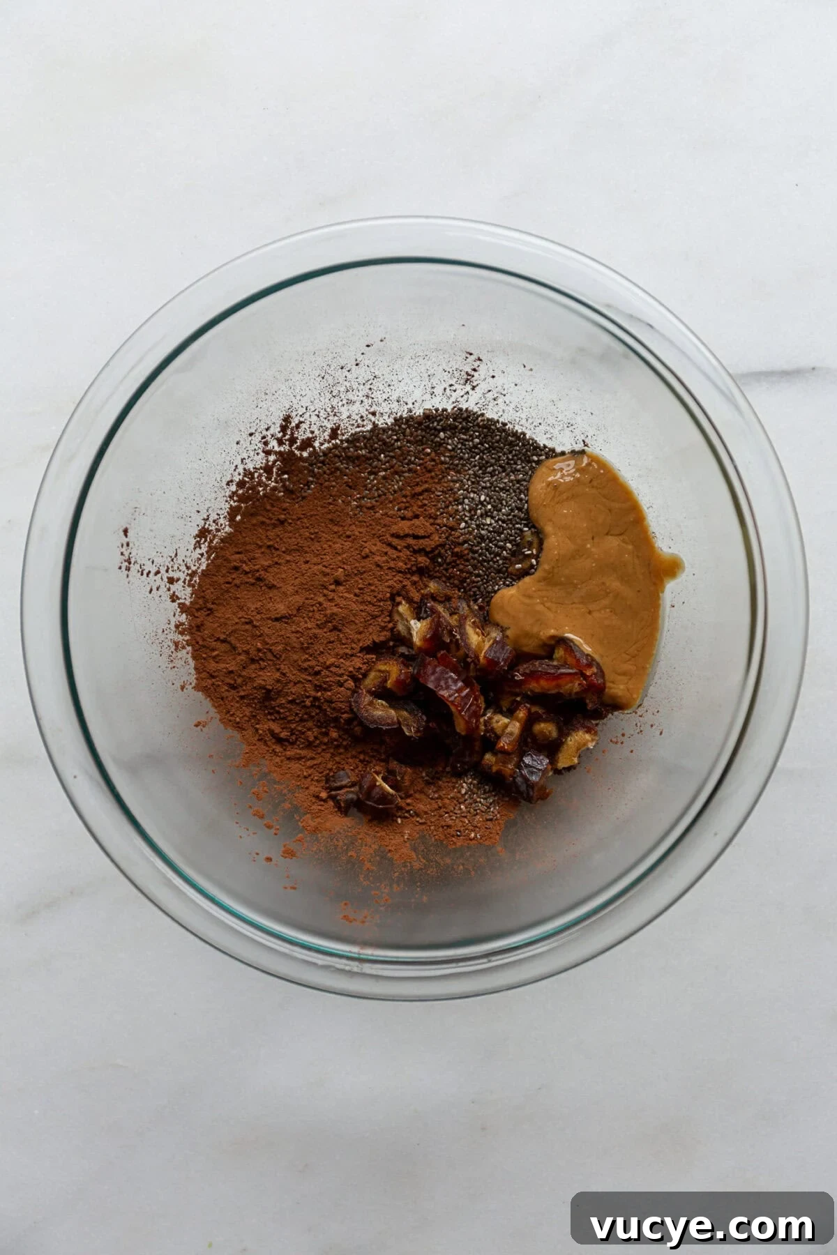 Snickers-Inspired Chia Pudding Recipe: Chocolate Peanut Butter Parfait 4 chia seeds, cocoa, peanut butter and dates in a clear mixing bowl.