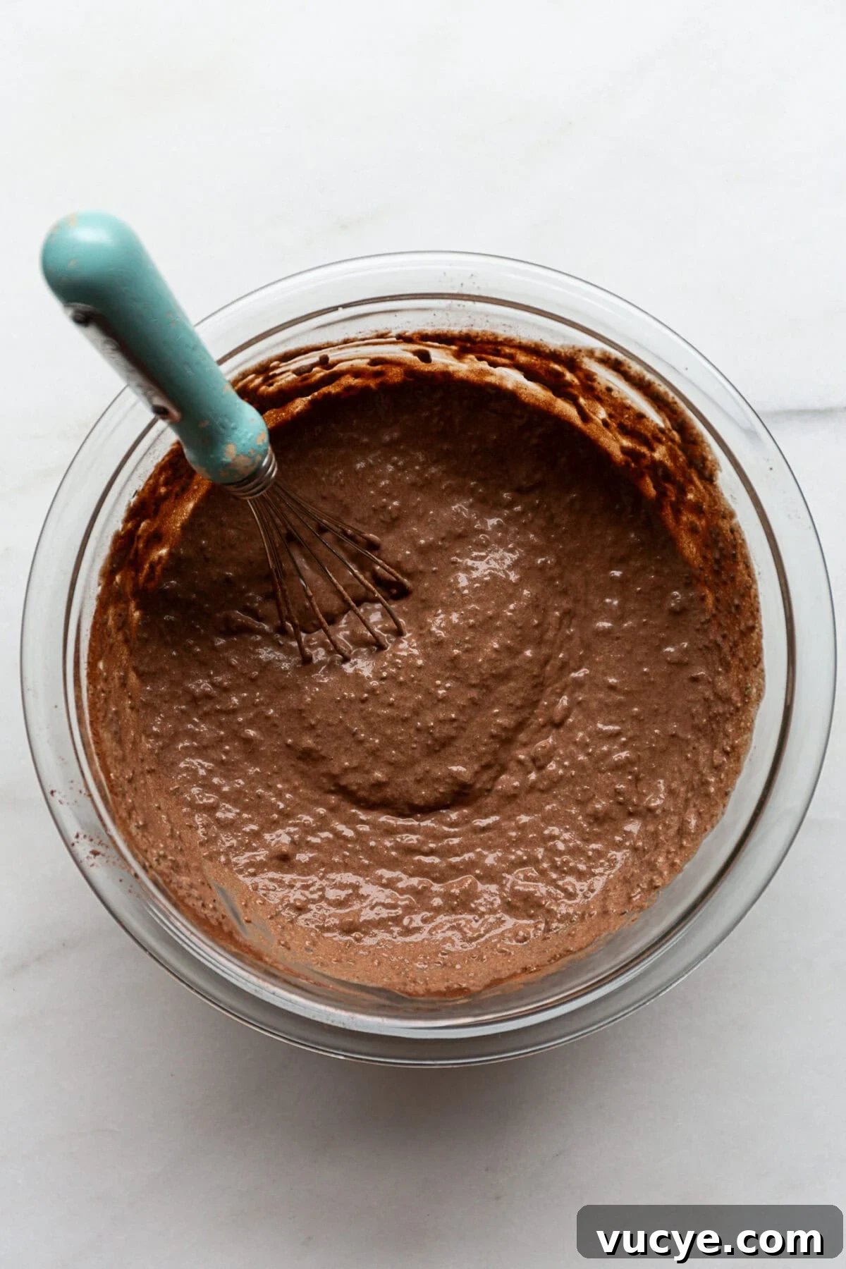 Snickers-Inspired Chia Pudding Recipe: Chocolate Peanut Butter Parfait 6 snickers chia pudding in a mixing bowl with a blue whisk in it.
