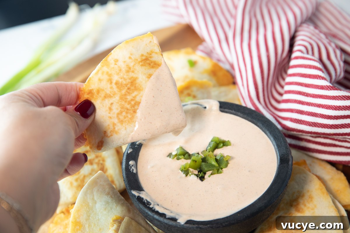 Taco Bell Quesadilla Sauce: Copycat Recipe & Serving Tips 8 womans hand holding quesadilla dipped in taco bell quesadilla sauce