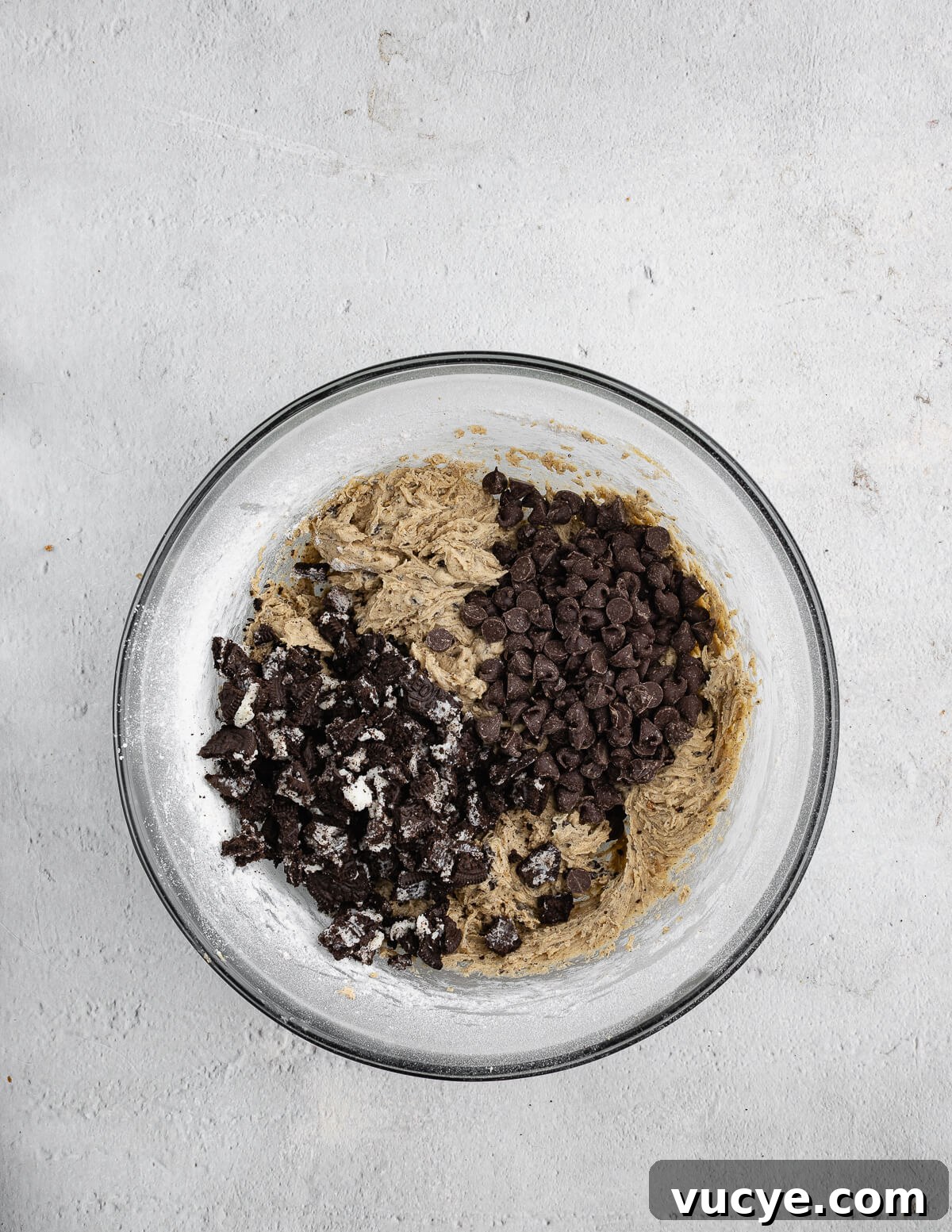 Oreo Chocolate Chip Cookies Recipe — Crispy Edges, Chewy Center 13 a bowl of cookie dough with Oreo pieces and chocolate chips on top.