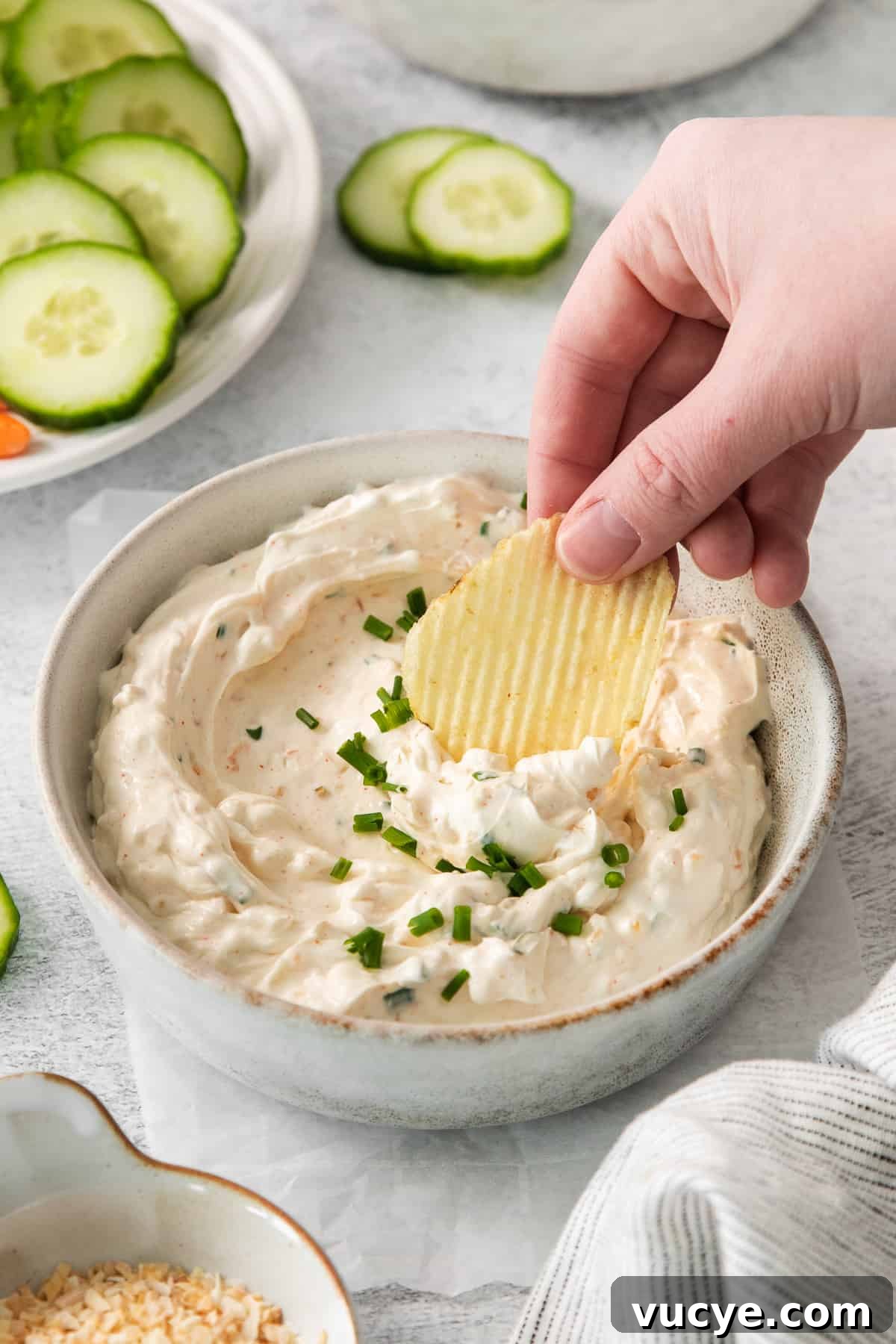 Potato chip being dipped into chip dip in a bowl.