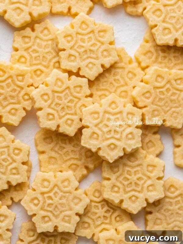 Classic Chewy Snickerdoodle Cookie Recipe for Perfect Cinnamon Cookies 11 Butter cookies shaped as snowflakes randomly placed on a white parchment paper lined baking sheet.