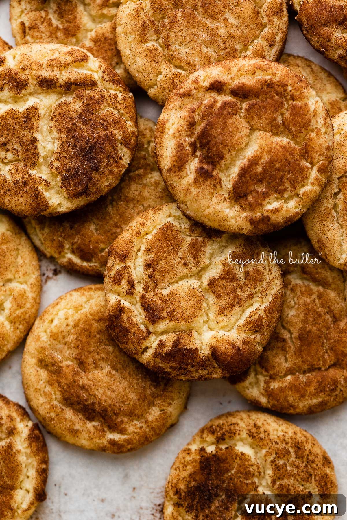 Classic Chewy Snickerdoodle Cookie Recipe for Perfect Cinnamon Cookies 5 Piled snickerdoodle cookies on a parchment paper lined baking sheet | © Beyond the Butter®