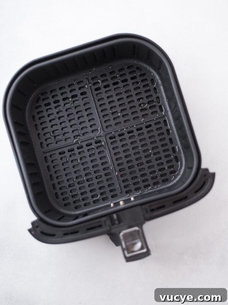 Crispy Air Fryer Sweet Potato Fries from Frozen 4 Avocado oil spray over the air fryer bucket.