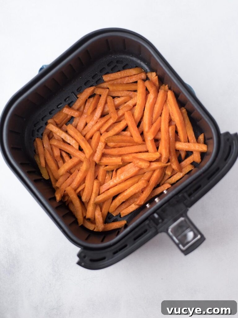 Crispy Air Fryer Sweet Potato Fries from Frozen 6 Cooked sweet potato french fries in the air fryer bucket.