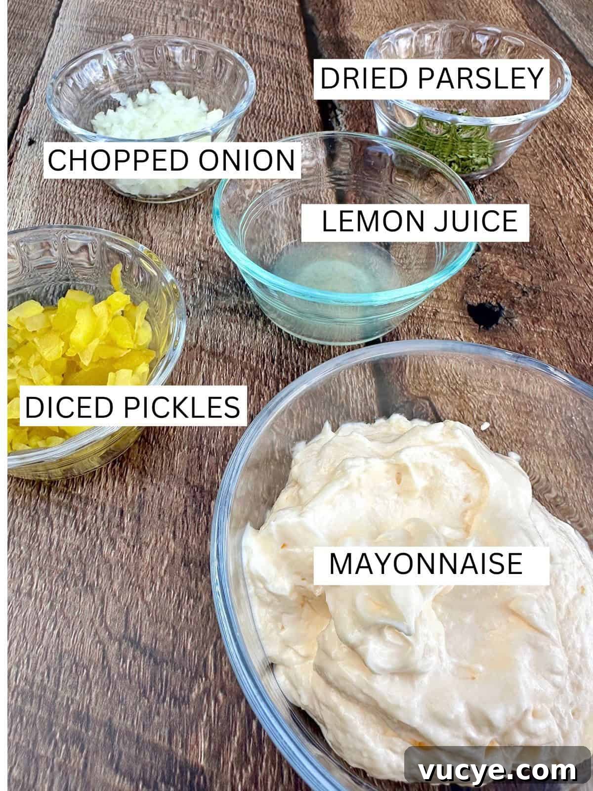 Homemade Tartar Sauce Recipe for Fish and Seafood 4 Tartar sauce ingredients in small bowls on a wooden board.