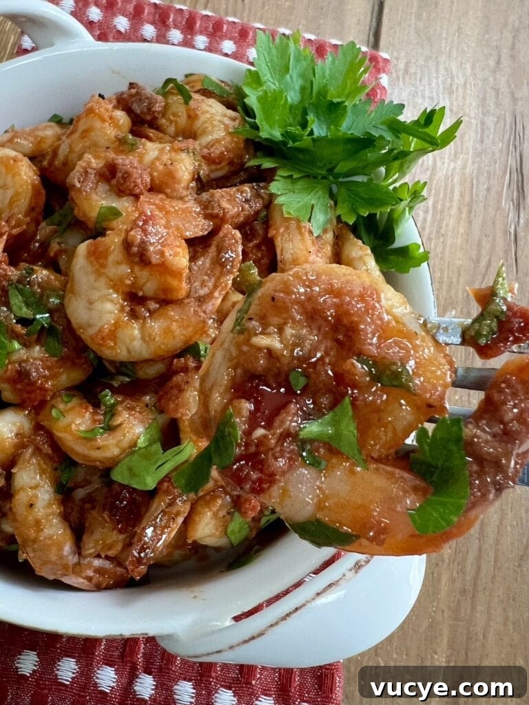 Close up of one piece of spicy shrimp fra diavolo recipe with a plate of them in the background.
