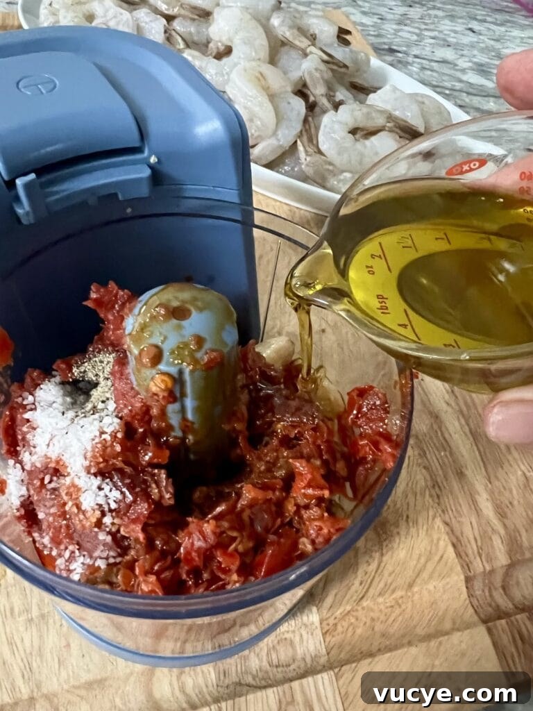 Pouring olive oil into food processor with other marinade ingredients.