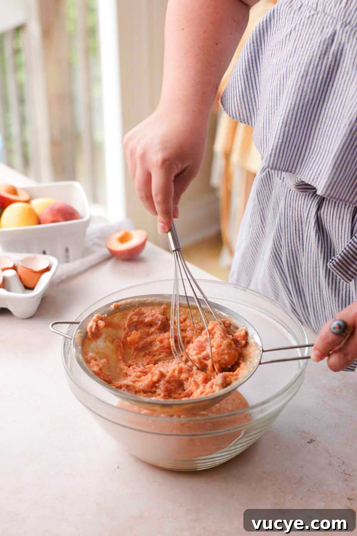 Silky Homemade Peach Curd Recipe for Tarts & Toast 12 straining peach curd through a sieve with a whisk