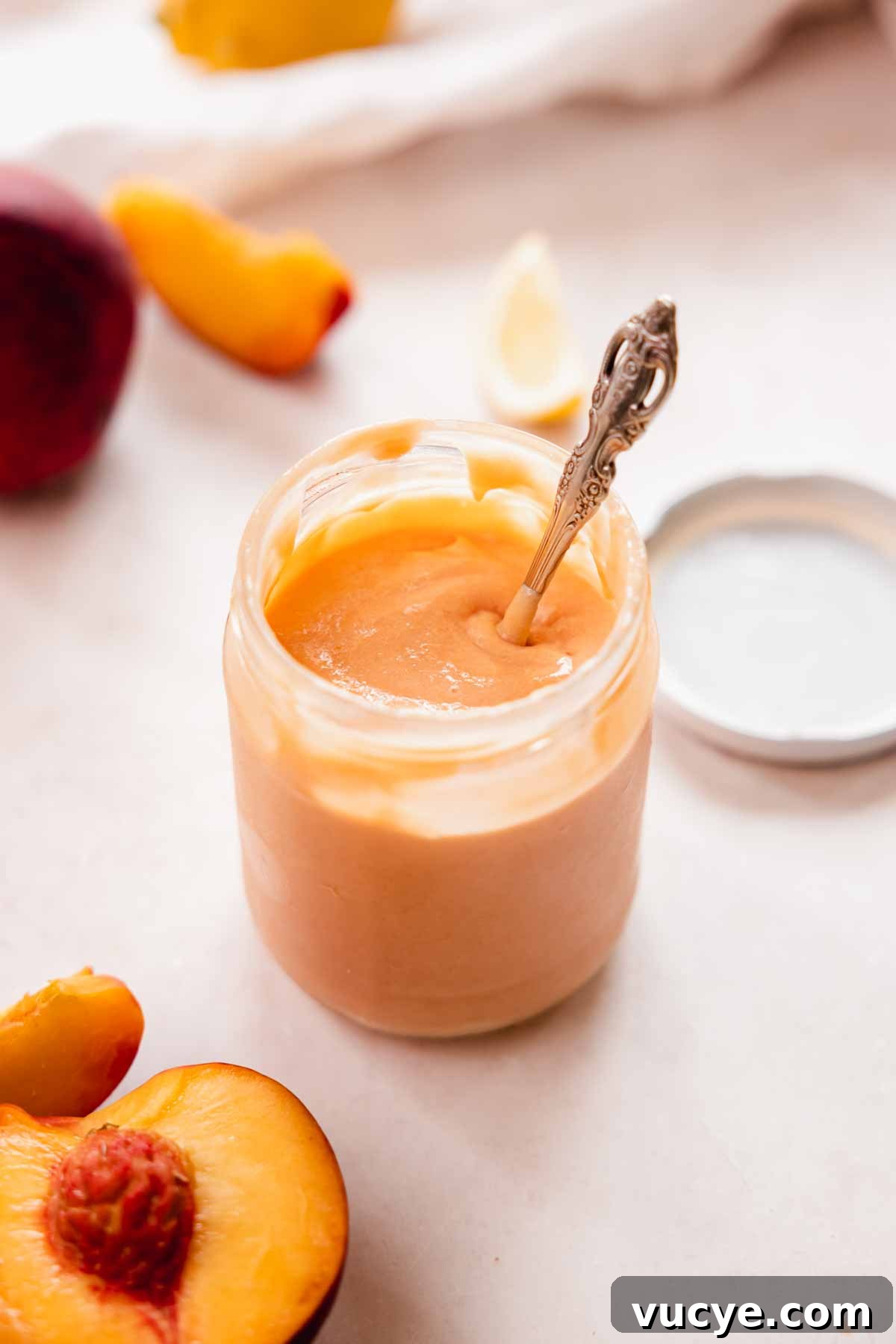 Silky Homemade Peach Curd Recipe for Tarts & Toast 15 peach curd in a glass jar with a spoon inside