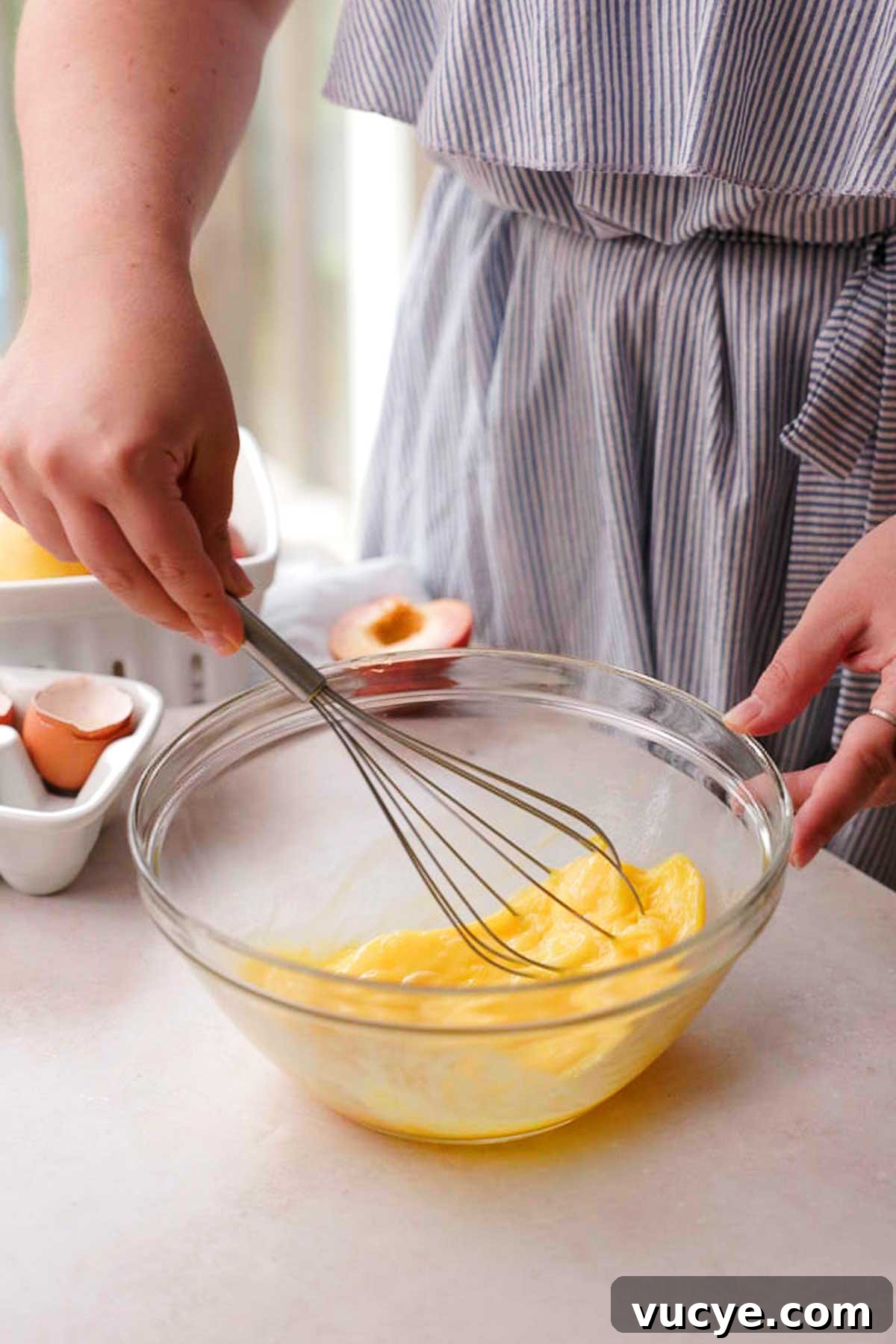Silky Homemade Peach Curd Recipe for Tarts & Toast 9 whisking eggs with a hand held whisk in a glass bowl