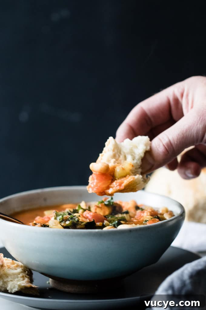 Hearty white bean minestrone is a veggie loaded warming spin on the Italian classic. This soup is full of veggies and protein to keep winter colds at bay and it's got a depth of flavour from pancetta and cavolo nero. A nod to classic Italian ingredients. White bean minestrone in a bowl with bread and parmesan cheese.