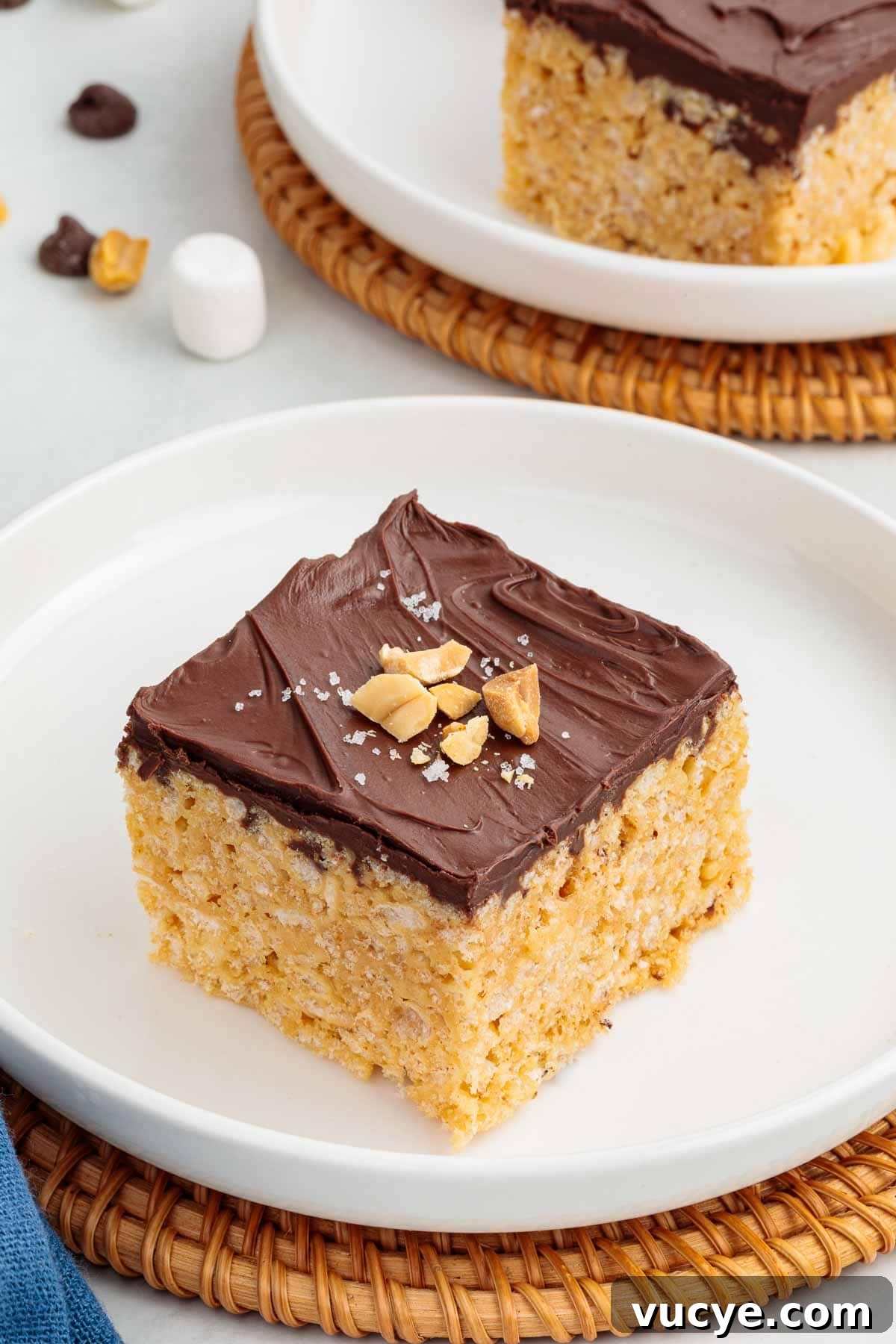 A peanut butter Rice Krispie treat topped with a smooth layer of chocolate, chopped peanuts, and a sprinkle of flaky salt.