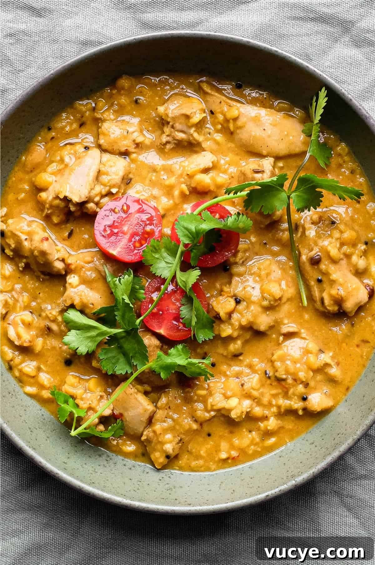 Chicken & Lentil Curry | cookeatworld.com A bowl of lentil curry garnished with some cherry tomatoes and a little cilantro