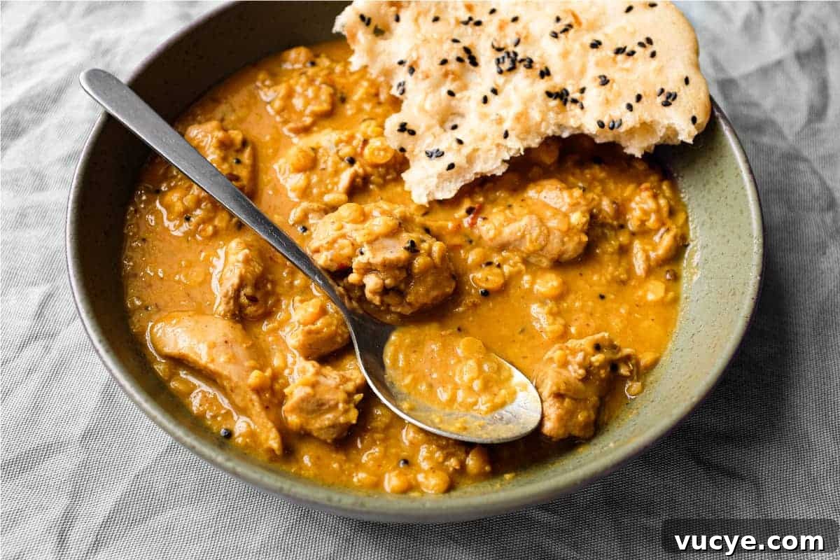 Chicken and Lentil Curry Recipe for Tender, Flavorful One-Pot Meal 2 A bowl of lentil curry with a spoon and piece of naan bread