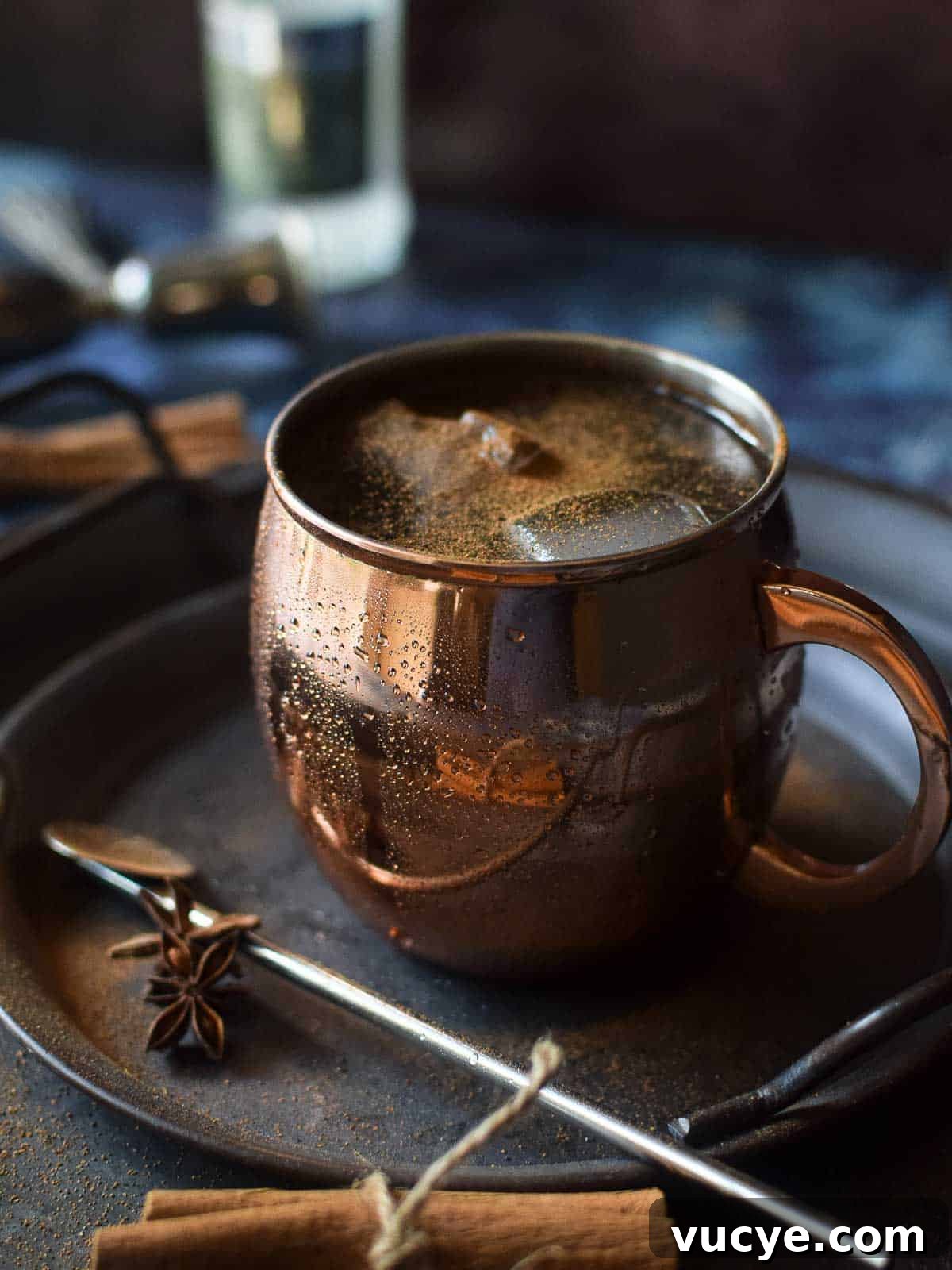 Close up of chai moscow mule in a copper mug with cinnamon stick and whole anise.
