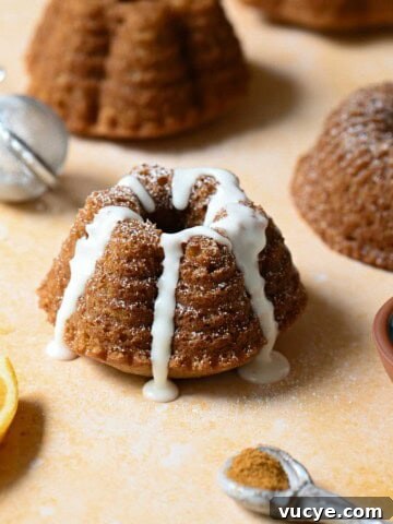 Mini mace bundt cake with white glaze on an orange surface.