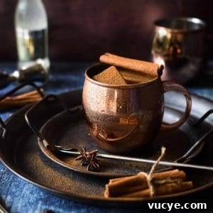 Chai Moscow mule in a copper mug with a cinnamon stick on fire.