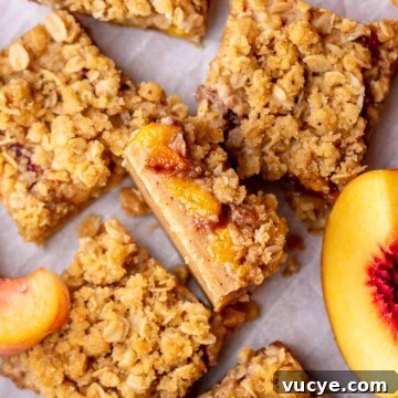 A slice of peach crumble bars sliced laying on its side.
