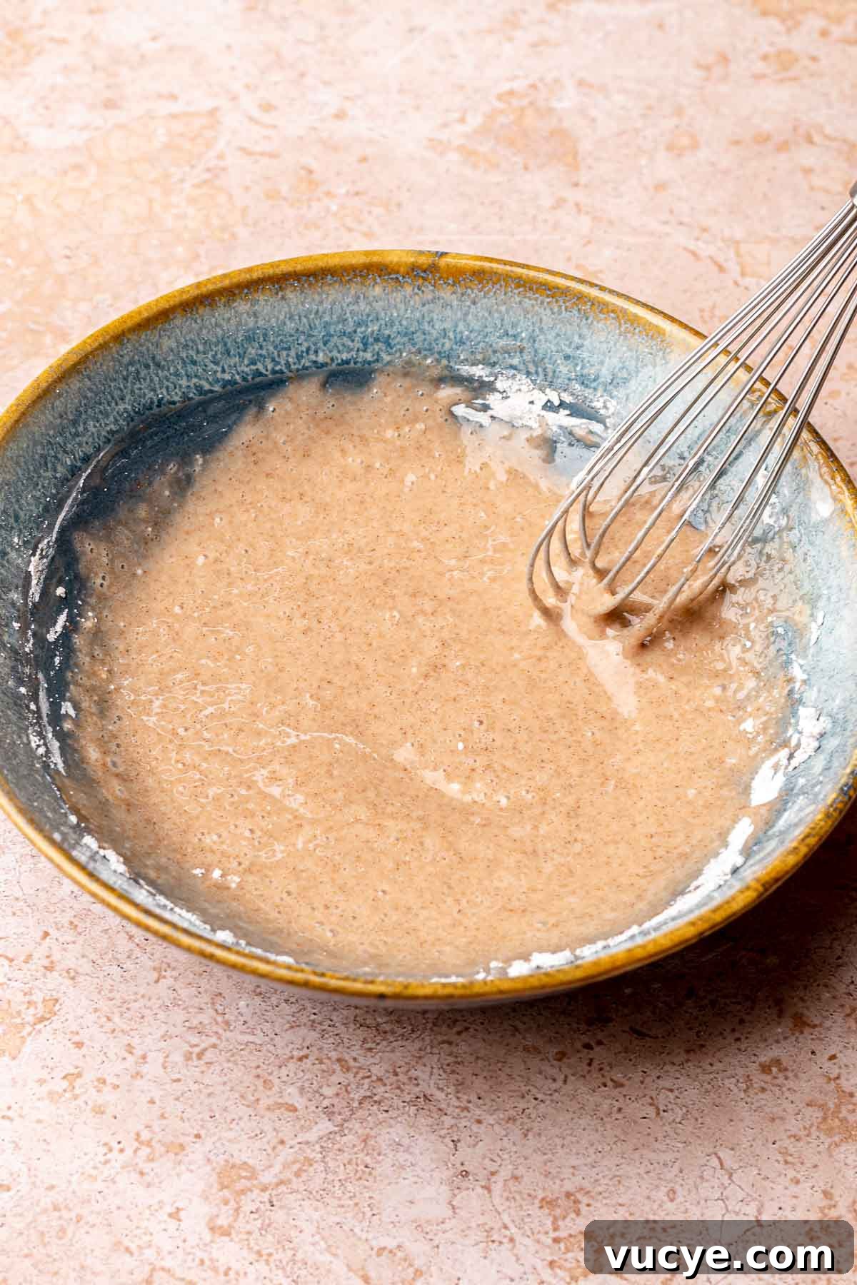 Apple Cinnamon Blondie Recipe — Chewy Spiced Apple Bars 8 A whisk mixes cinnamon icing in a bowl.